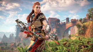 Aloy in Horizon Zero Dawn Remastered, she's stood holding her bow and arrow, a bridge and town seen in the background.