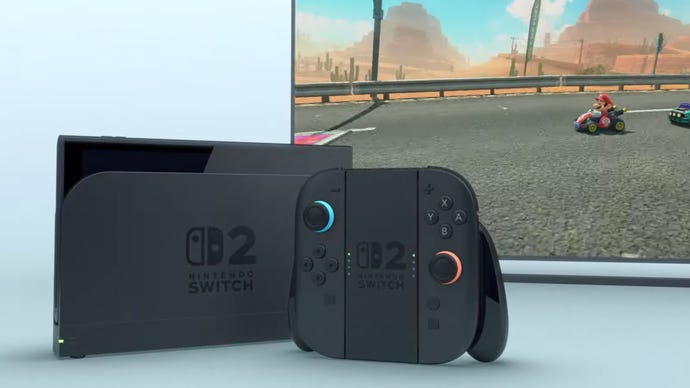 A docked Nintendo Switch 2 with an untitled Mario Kart game playing on a TV behind it.